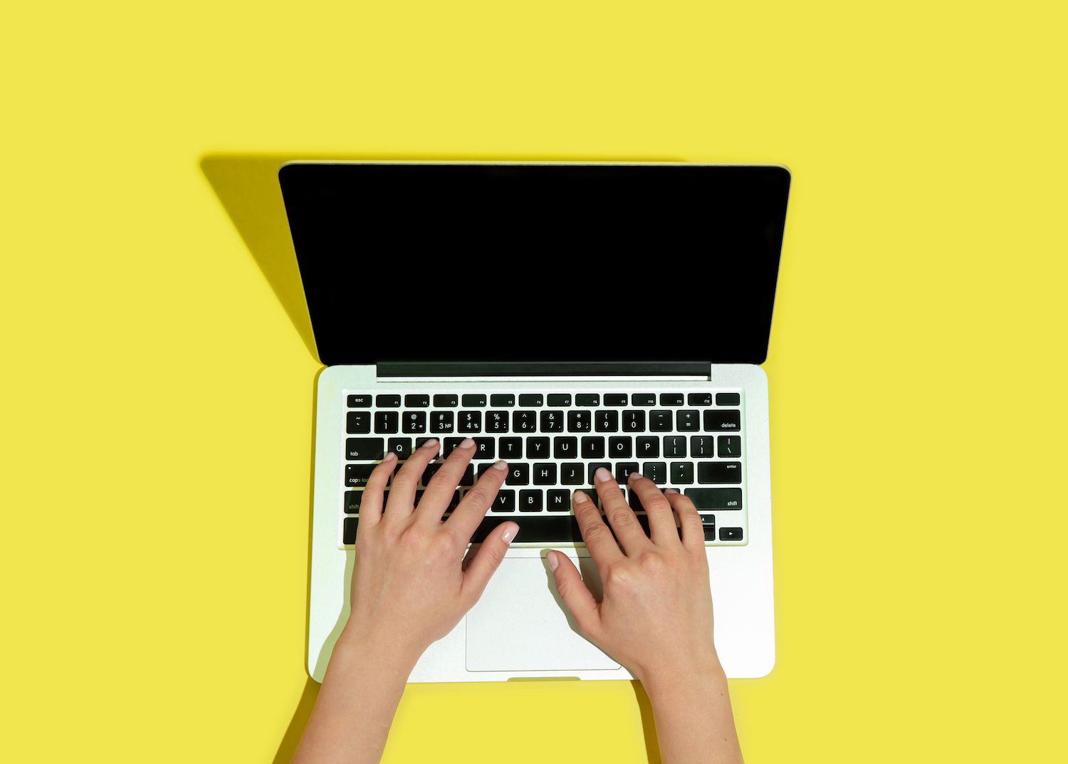 woman leaning against a couch looking at a laptop